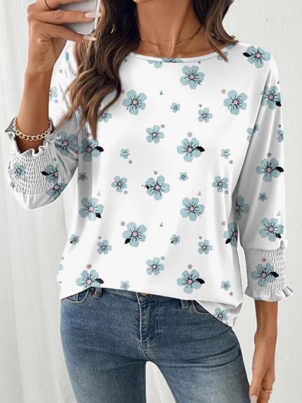 Lightweight white top with a delicate blue floral print. Features smocked cuff d